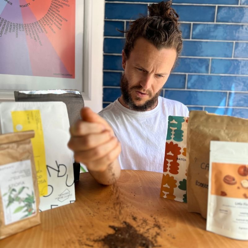 Tom Saxon brewing a V60 pour over on a scale beside bags of Batch coffee