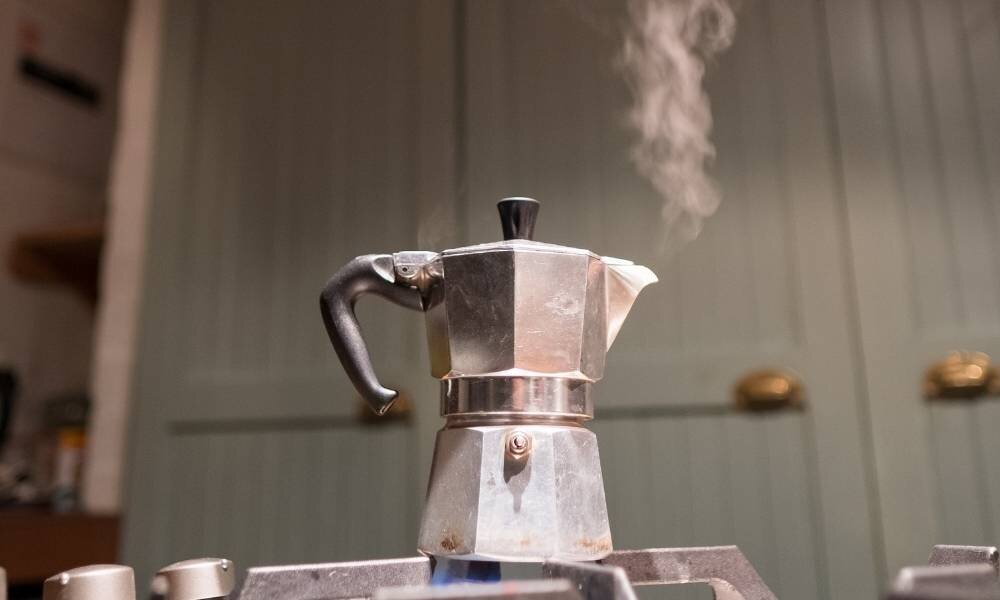 A moka pot steaming on the stove
