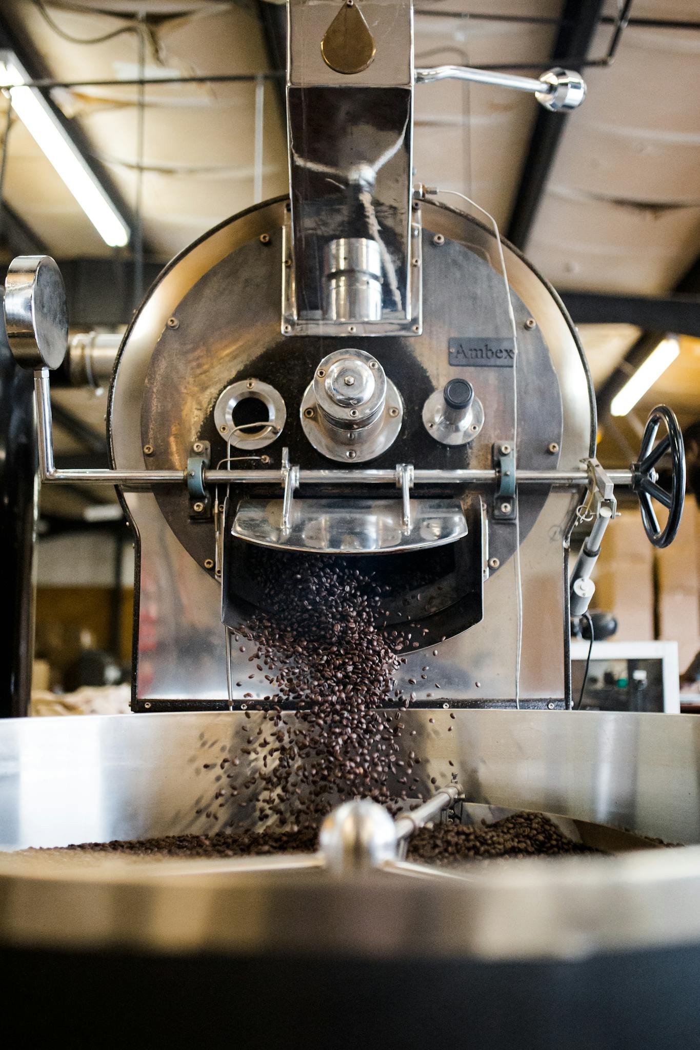 Why Is Coffee So Expensive Right Now? A Roaster Explains 3 Coffee beans pouring out of a drum roaster into the cooling tray