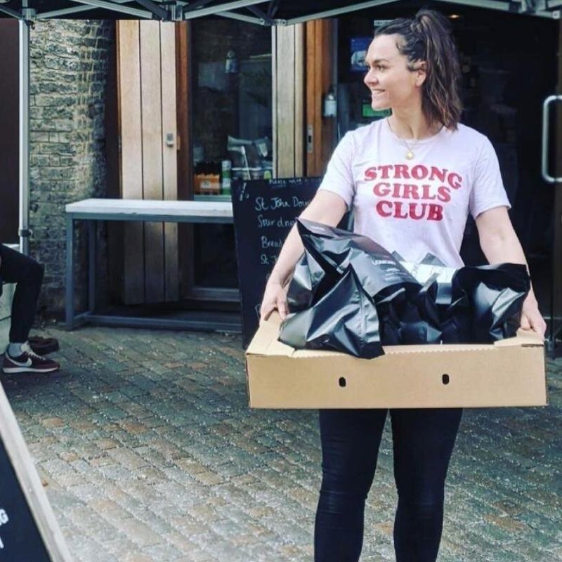A Lomond Coffee Roasters team member carrying a box of coffee bags outside the Deptford roastery